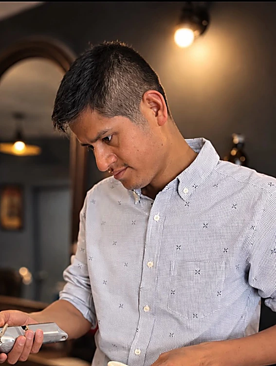 Josué Mancilla, de camisa clara, perfilando una barba con máquina